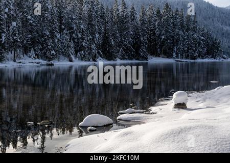 Soleil Shining sur des rochers enneigées le long du lac STILL en hiver Banque D'Images