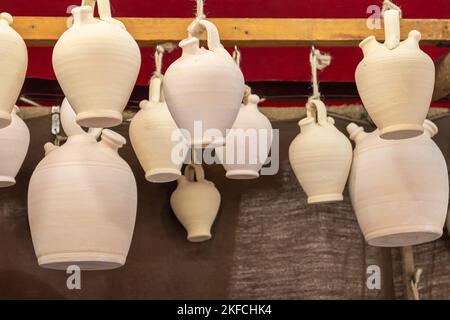 gros plan en vue horizontale de plusieurs botijos blancs d'argile suspendus au plafond. botijo est une carafe à boire avec bec Banque D'Images