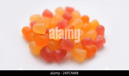 Mise au point sélective, texture de gros plan des gommies multivitaminées orange et jaune sur fond blanc Banque D'Images