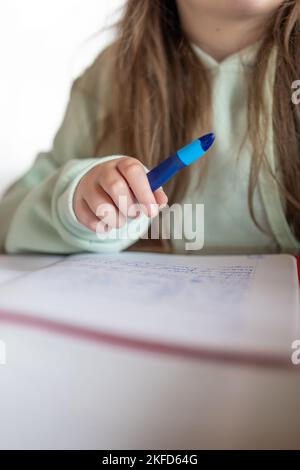 Devoirs.étudier et éducation.Schoolgirl fait ses devoirs. L'enfant écrit avec un crayon dans un bloc-notes.gros plan crayon dans une main d'enfant. Banque D'Images