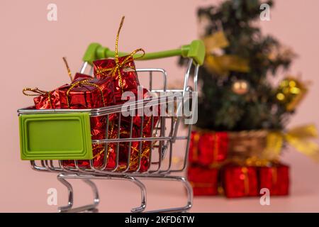 Panier de Noël avec cadeaux et arbre de Noël en arrière-plan sur fond rouge clair Banque D'Images