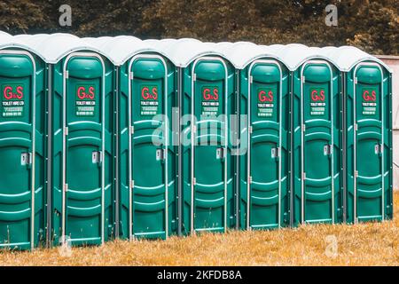 Une ligne de toilettes portables sur l'herbe à l'extérieur. Banque D'Images