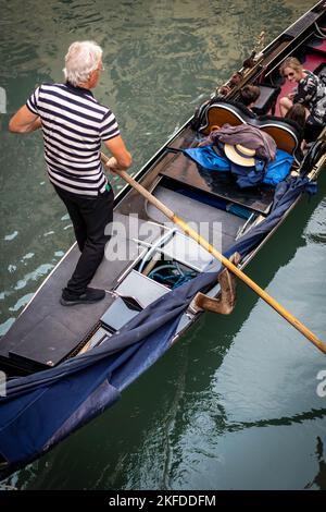 Gondolier à la tête d'une gondole, un bateau à rames vénitien traditionnel sur un canal à Venise, en Italie Banque D'Images