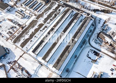 zone industrielle avec des bâtiments de fabrication couverts de neige, des entrepôts, des équipements industriels. vue aérienne en hiver. Banque D'Images