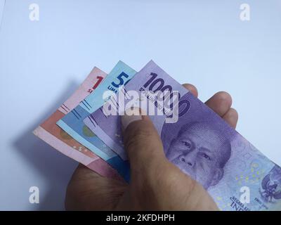 Gros plan isolé sur main blanche tenant de l'argent plusieurs billets libellés en rupiah. La rupiah est la monnaie de l'Indonésie Banque D'Images