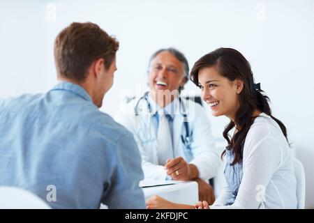 Médecin mature et patients ayant une conversation saine. Portrait d'un médecin heureux et de jeunes patients ayant une conversation saine en clinique. Banque D'Images