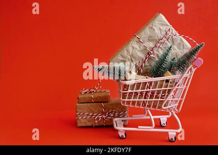 Soldes de Noël - Panier et cadeaux de Noël sur fond rouge. Joyeux Noël, concept de shopping de la nouvelle année. Vue de dessus et espace de copie. Banque D'Images