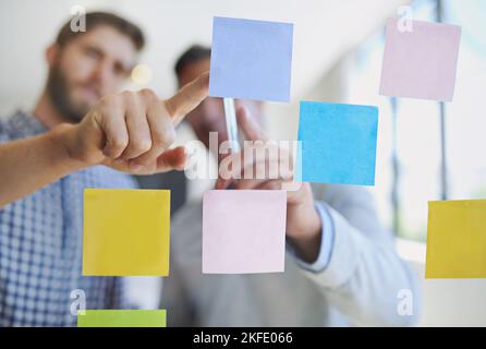 La conception est visible. À travers la photo de deux collègues de sexe masculin, en organisant des notes adhésives sur un mur pendant une réunion. Banque D'Images