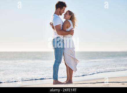 Hug, plage et couple heureux lors de vacances romantiques pour l'amour ensemble au bord de l'océan en Australie. Voyage, romance et jeune homme et femme embrassant Banque D'Images