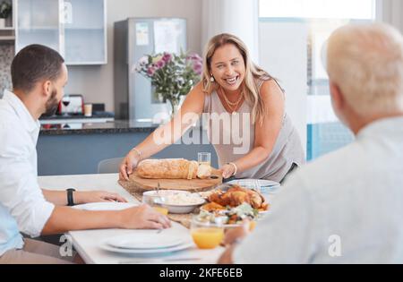 Déjeuner, célébration et famille heureuse avec la nourriture à une table de salle à manger pendant les vacances à l'hébergement. Service, dîner et femme âgée avec du pain et Banque D'Images