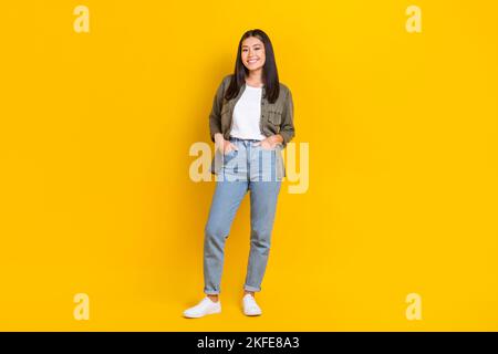 Pleine longueur de corps photo de jeune sourire mignon affaires coréen dame IT entreprise propriétaire décontracté ensemble mains poches isolées sur fond jaune couleur Banque D'Images