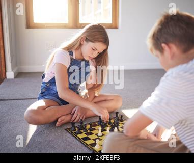 Enfants, échecs et jeu de société avec une fille et un garçon jouant sur le plancher de leur maison ensemble. Cerveau, pensée et stratégie avec un frère et une sœur Banque D'Images