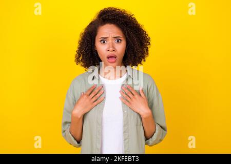 Photo de la coiffure ondulée stressée jeune femme index elle-même porter chemise grise isolée sur fond jaune Banque D'Images