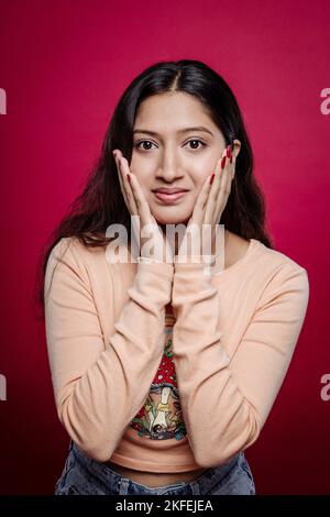 Charmante femme avec une peau douce appliquant des cosmétiques faciaux et touchant son visage. Une belle femme avec Radiant, Soft Skin promotion commercial Advertis Banque D'Images