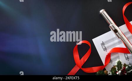 Fond avec flûte en métal sur la feuille de musique sur la table noire avec des spots et la décoration de Noël. Vue de dessus. Banque D'Images