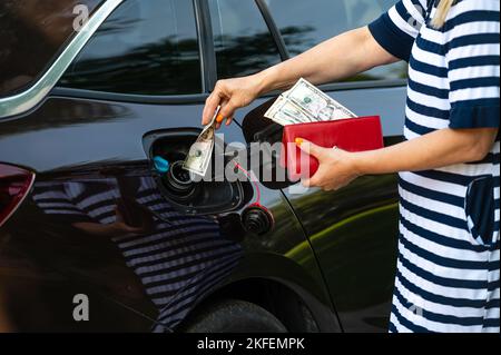 main de femme qui met l'argent dans le réservoir de voiture, gros plan, concept de carburant coûteux, crise de carburant Banque D'Images