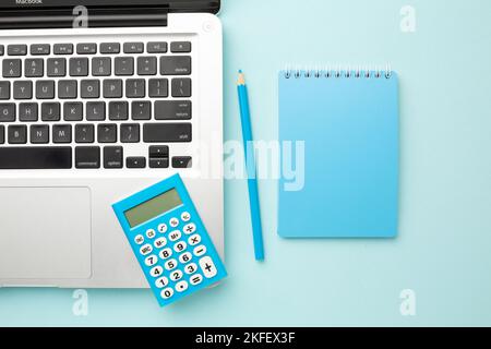 Bureau bleu table de travail avec ordinateur portable, ordinateur portable, crayon, calculatrice. Vue de dessus avec espace de copie. Banque D'Images