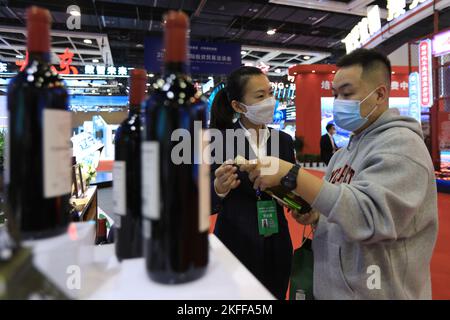 (221118) -- SHENYANG, 18 novembre 2022 (Xinhua) -- Un visiteur regarde une bouteille de vin pendant qu'un exposant élabore une exposition lors du salon international de l'investissement et du commerce de Liaoning 2022 à Shenyang, dans la province de Liaoning, dans le nord-est de la Chine, le 18 novembre 2022. Le salon international de l'investissement et du commerce de Liaoning de 2022 a débuté ici vendredi. Thématique « étendre la voie d'ouverture, partager le développement vert », la foire vise à promouvoir les réalisations de la revitalisation et du développement du Liaoning, et à stimuler la coopération économique et commerciale entre la province et d'autres parties. (Xinhua/Wang Yij Banque D'Images