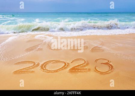 2023 écrit sur le sable d'une plage, les vagues de l'océan, voyage carte de voeux de nouvel an Banque D'Images