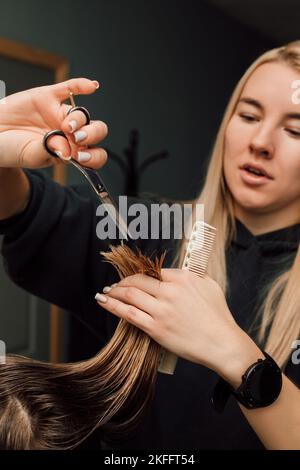 Un coiffeur coupe les cheveux d'un client.dans les mains des ciseaux de coiffeur et des cheveux Banque D'Images