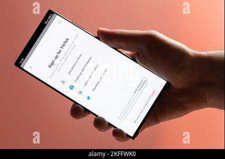 New york, Etats-Unis - 10 novembre 2022 : inscrivez-vous à TikTok sur votre smartphone en tenant à la main en gros plan sur fond rose Banque D'Images