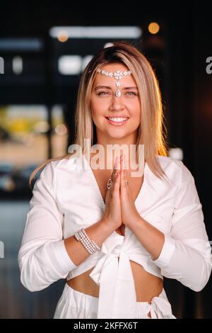 Portrait d'une fille souriante dans une robe blanche avec ses paumes clastées devant elle Banque D'Images