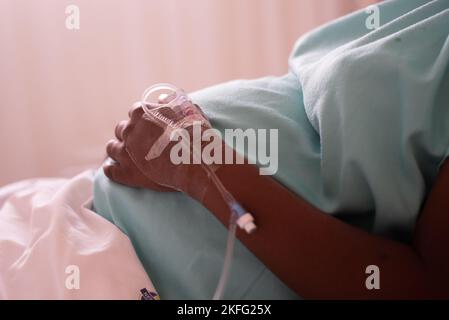 Femme enceinte au travail, couchée dans un lit d'hôpital attendant la naissance de son bébé. Banque D'Images