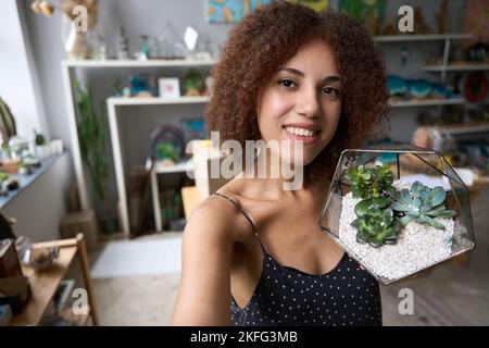 Fleuriste féminin de talent tenant un contenant en verre avec des succulents Banque D'Images