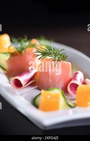 Buffet de tranches de saumon marinées avec radis, concombre et cubes d'orange Banque D'Images