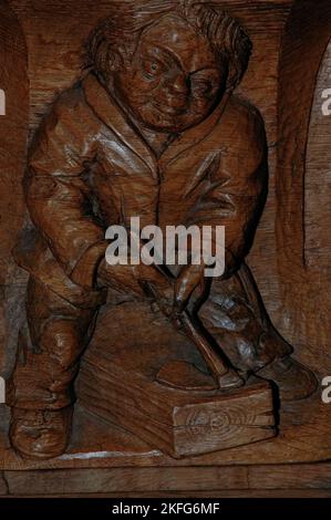 Le sculpteur néerlandais Joop van Huisstede (1922-2000) aurait rendu hommage à un membre de confiance de l'équipe travaillant avec lui pour restaurer l'Oude Kerk (ancienne église) à Amsterdam, pays-Bas, En dépeignant l'ouvrier Jan Hop dans ce misericord de décrochage de choeur sculpté de 1974 montrant un homme utilisant une adze pour raser un baume de bois. Banque D'Images