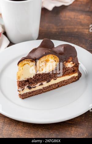 Gâteau avec profiteroles sur une assiette en porcelaine blanche avec café filtre sur le côté Banque D'Images