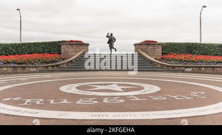 Statue d'Eric Morecambe sur le front de Morcambe se, Royaume-uni. Célèbre sculpture d'art avec des fleurs symétriques de chaque côté et des pavés circulaires. Banque D'Images