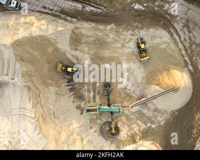 Pelle hydraulique chargeant du sable dans une benne dans une carrière de sable, extraction industrielle de sable pour l'industrie de la construction Banque D'Images