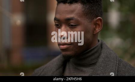 Beau jeune homme noir debout à l'extérieur pensant Banque D'Images