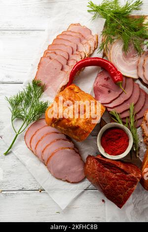 Vue en hauteur sur les tranches de viande fumée, épice et herbes sur bois blanc Banque D'Images