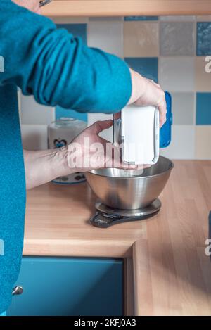 homme pesant de la farine dans la cuisine pèse-personne. Côté de l'homme et mains visibles. Banque D'Images