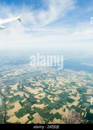 Image rognée d'une aile d'avion volante contre le ciel et vue panoramique sur le paysage de patchwork Banque D'Images