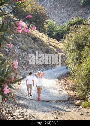 Vue arrière de la mère et du fils caucasiens randonnée sur la route de terre au milieu des plantes tout en appréciant les vacances Banque D'Images