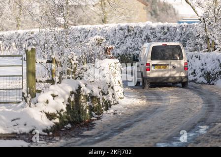 Minibus blanc qui longe la voie de campagne dans le givre et la glace. Pistes de neige sur la voie Banque D'Images