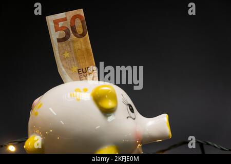 Un billet de cinquante euros dans une banque de porc, sur un fond sombre. Vue latérale. Concept d'économie d'argent. copier l'espace. Banque D'Images