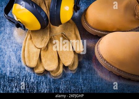 Jeu de bottes de sécurité gants en cuir et casque de réduction du bruit sur surface métallique rayée concept de construction. Banque D'Images