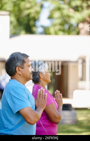 Namaste. Portrait d'un couple mature faisant du yoga ensemble dans leur arrière-cour. Banque D'Images