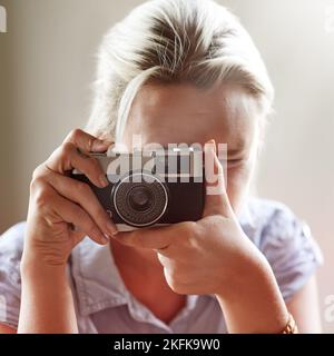 Capturer la vie. Gros plan d'une jeune femme prenant une photo avec un appareil photo à l'ancienne. Banque D'Images