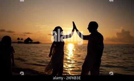 Les familles sur la plage. Silhouette de coucher de soleil haute cinq Banque D'Images