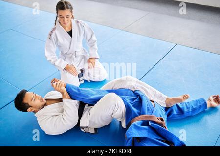 Karaté, entraîneur personnel et autodéfense formation dans le dojo pour la protection physique ou la santé et la sécurité. Ceinture noire sensei homme enseignant femme à Banque D'Images