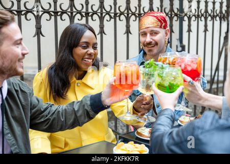 Groupe de personnes diverses qui toastent des boissons au bar à cocktails, des amis qui s'amusent pendant la rencontre, se concentrent sur la femme afro-américaine, les gens qui boivent du mojit Banque D'Images