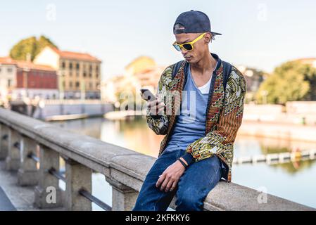 Jeune homme branché regardant son smartphone, un homme accro au réseau social vérifiant l'e-mail, le message en ligne, la création de contenu pour sa page personnelle et l'utilisation Banque D'Images