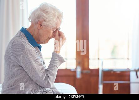 Femme âgée, mal de tête et stress avec anxiété dans la maison de retraite, seule et triste avec la santé mentale. Femme âgée, dépression et frustrée Banque D'Images