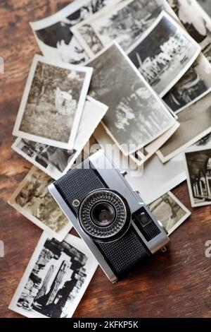 Instantanés du passé. Un appareil photo à l'ancienne situé au-dessus d'une pile de photos en noir et blanc. Banque D'Images