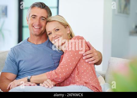 L'amour décontracté à la maison. Portrait d'un couple affectueux et mûr se reposant sur le canapé à la maison. Banque D'Images